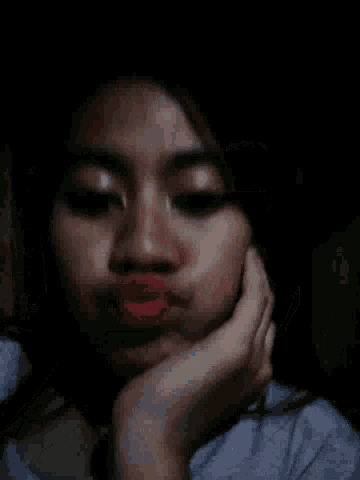 a woman with red lipstick is smiling with her hand on her face