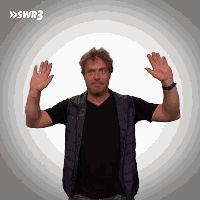 a man is waving his hands in front of a swr3 sign