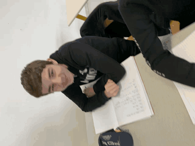 a boy wearing a black nike shirt sits at a table