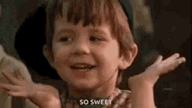 a little boy is smiling and making a funny face with his hands outstretched .