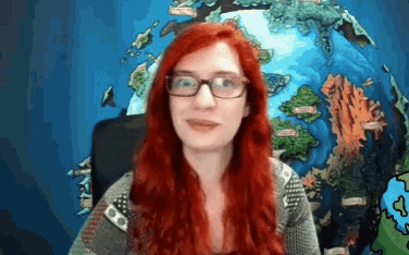 a woman with red hair wearing glasses stands in front of a globe