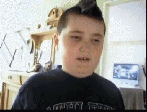 a young boy with a mohawk wearing a shirt that says ' army '