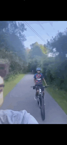 a person riding a bike down a path with a shirt that says ' avengers ' on it