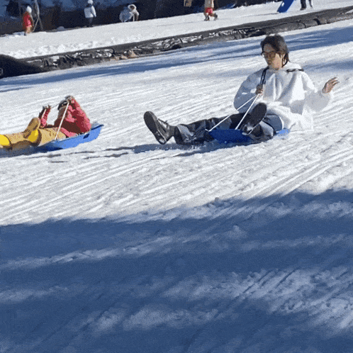 a woman and child sledding down a snow covered slope