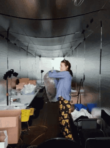 a woman is carrying a large bag in a room with boxes
