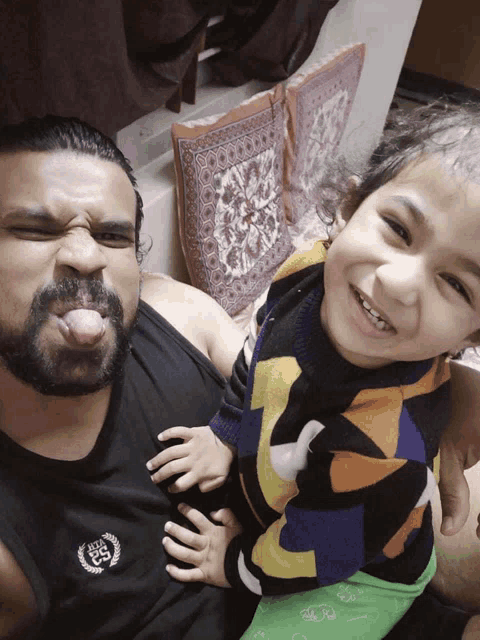 a man with a beard is holding a child who is wearing a shirt with the letters ec on it
