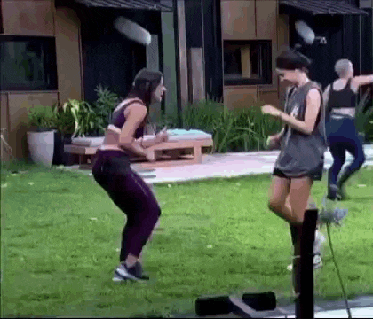 a group of women are dancing in a yard in front of a building .
