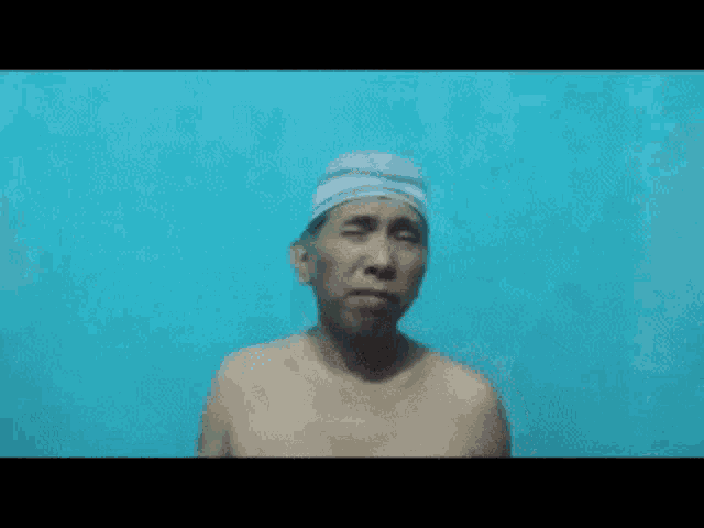a shirtless man wearing a white hat is making a funny face and giving the middle finger