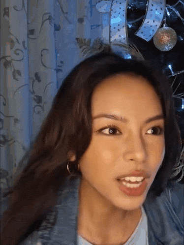 a close up of a woman 's face with christmas decorations in the background