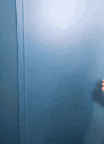 a person 's hand is reaching out towards a blue wall