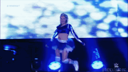 a female wrestler is jumping in the air in front of a large screen that says wwe