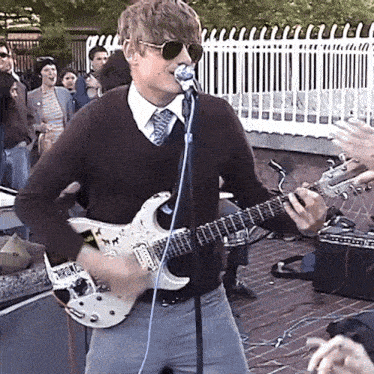 a man playing a guitar and singing into a microphone