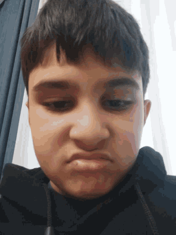 a close up of a boy 's face with a black jacket on