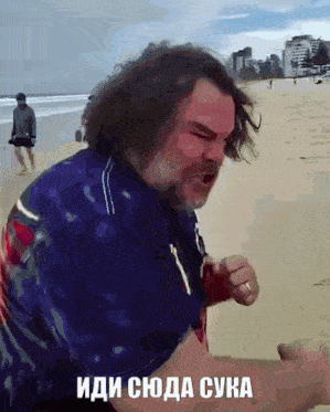 a man standing on a beach with the words " иди сюда сука " written on the bottom