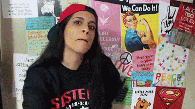 a woman standing in front of a wall with posters on it including one that says " we can do it "