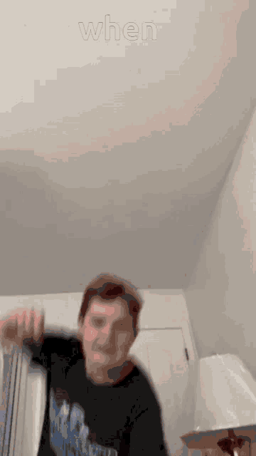 a man in a black shirt is dancing in a room with the words `` when '' written on the ceiling .