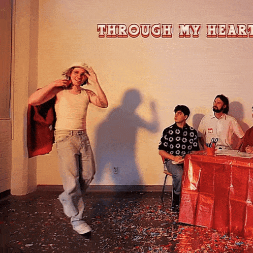 a man in a red cape stands in front of a wall that says through my heart