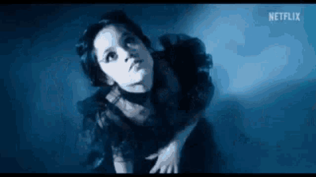 a woman in a black dress is looking up in the dark .