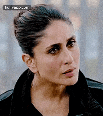 a close up of a woman 's face with a bun and a black jacket .