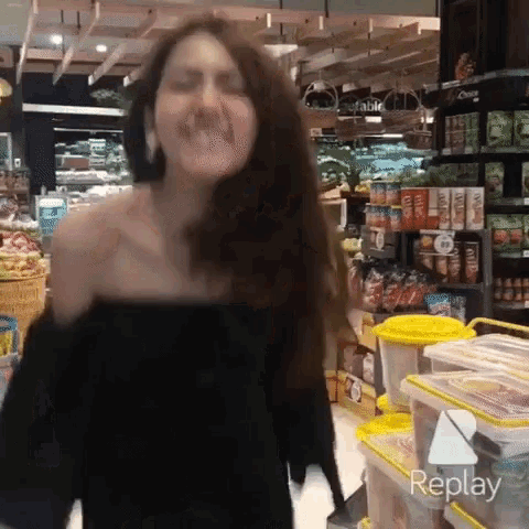 a woman in a black top is dancing in a store with replay written on the bottom right