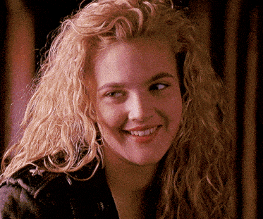 a woman with blonde curly hair is smiling for the camera