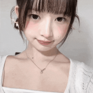 a close up of a girl wearing a necklace and a white top .