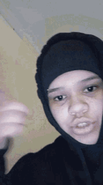 a woman wearing a black hooded jacket and a black hat