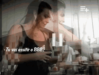 a woman in a black tank top is standing in a kitchen with the words tu vai assistir o bbb on the bottom right
