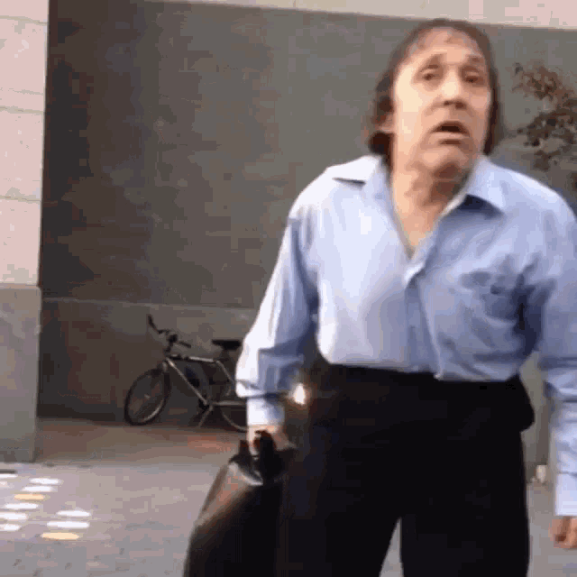 a man wearing a blue shirt and black pants is walking down the street