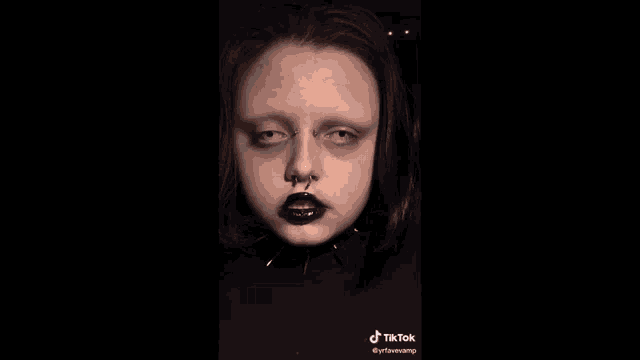 a close up of a person 's face with black lips and a nose ring .