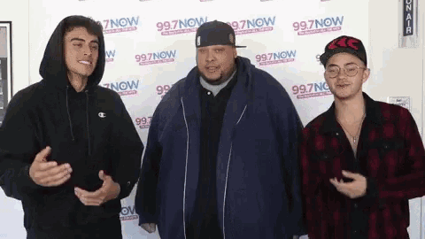three men standing in front of a wall that says 997 now