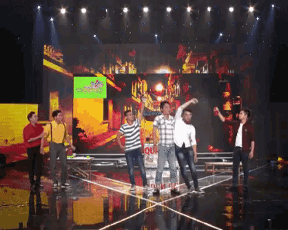 a group of men are standing on a stage with a large screen behind them that says ' evian ' on it