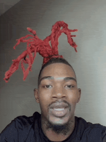 a man with red dreadlocks on his head smiles