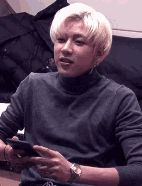 a man is sitting on a couch holding a cell phone in his hand .
