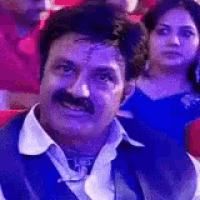 a man with a mustache is sitting in a theater with a woman .