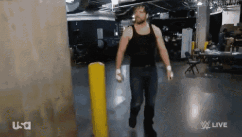 a man in a black tank top and jeans is walking through a room .