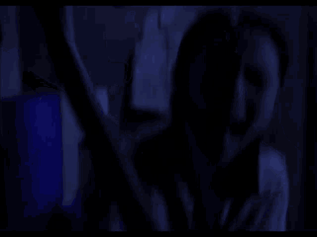 a blurry picture of a person in a dark room with clothes hanging on the wall .