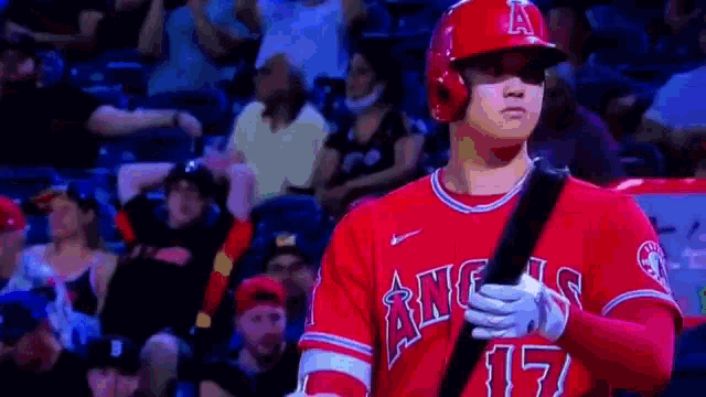 a baseball player is holding a bat in front of a crowd of people .