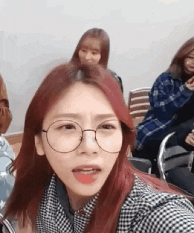 a woman with red hair and glasses is taking a selfie .