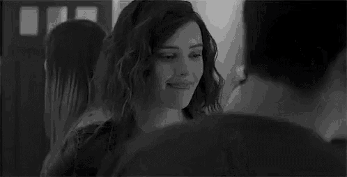 a black and white photo of a woman smiling in a crowd of people .