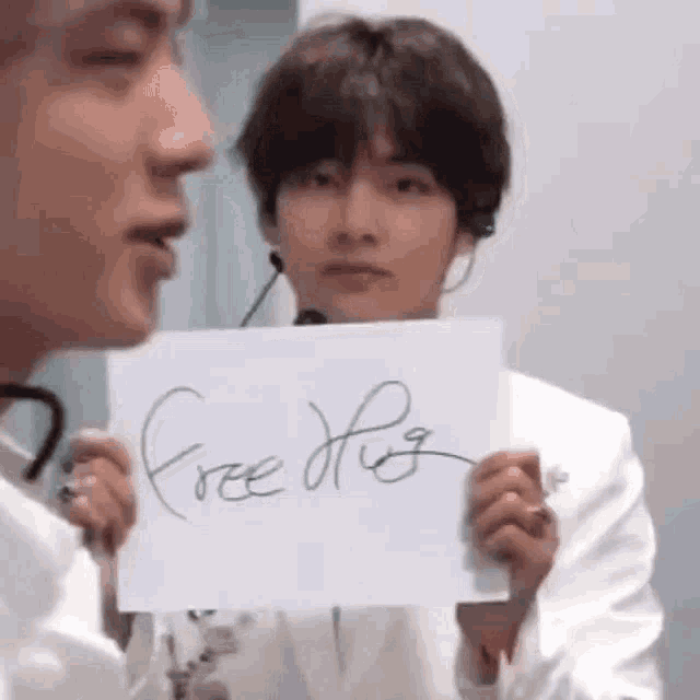 a man is holding a piece of paper that says `` free hug '' .
