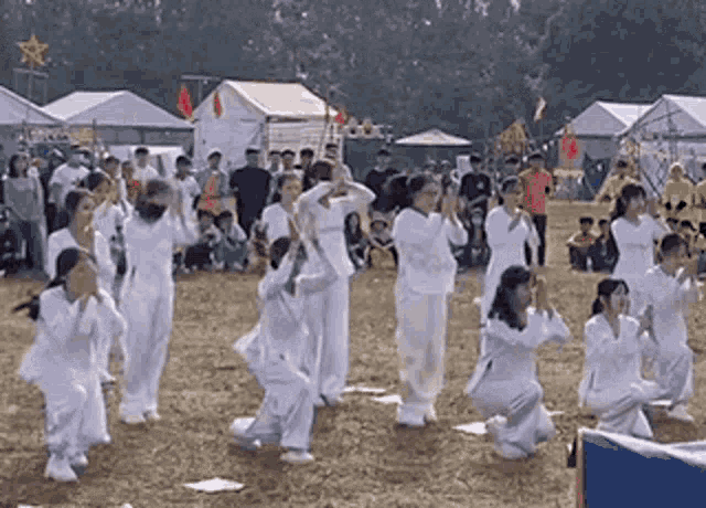 a group of people are dancing in a field in front of tents