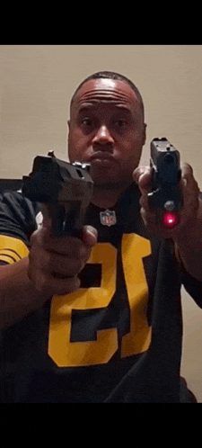 a man in a pittsburgh steelers jersey is holding two guns .