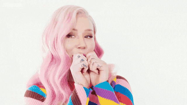 a woman with pink hair is wearing a colorful striped sweater .