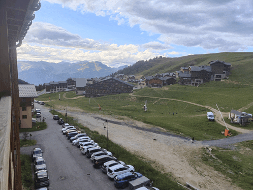 a row of cars are parked in front of a mountain village