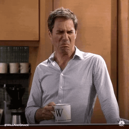 a man is holding a cup of coffee and making a face .