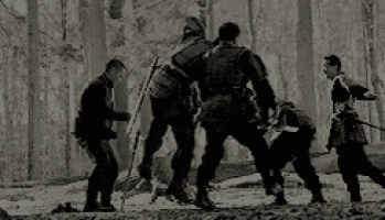 a group of men are kneeling down in the woods .