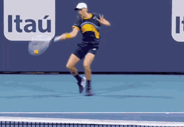 a tennis player is swinging a racket at a tennis ball in front of an itau sign