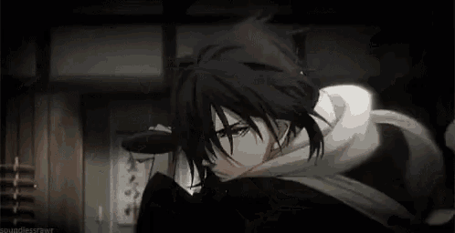 a man with long black hair and a scarf around his neck is standing in a dark room .