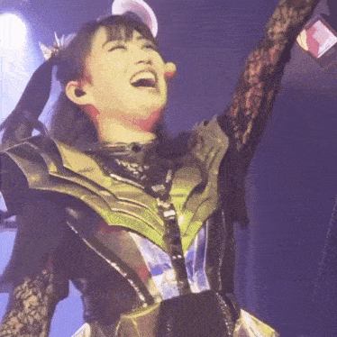 a woman in a metallic outfit is laughing and holding a microphone